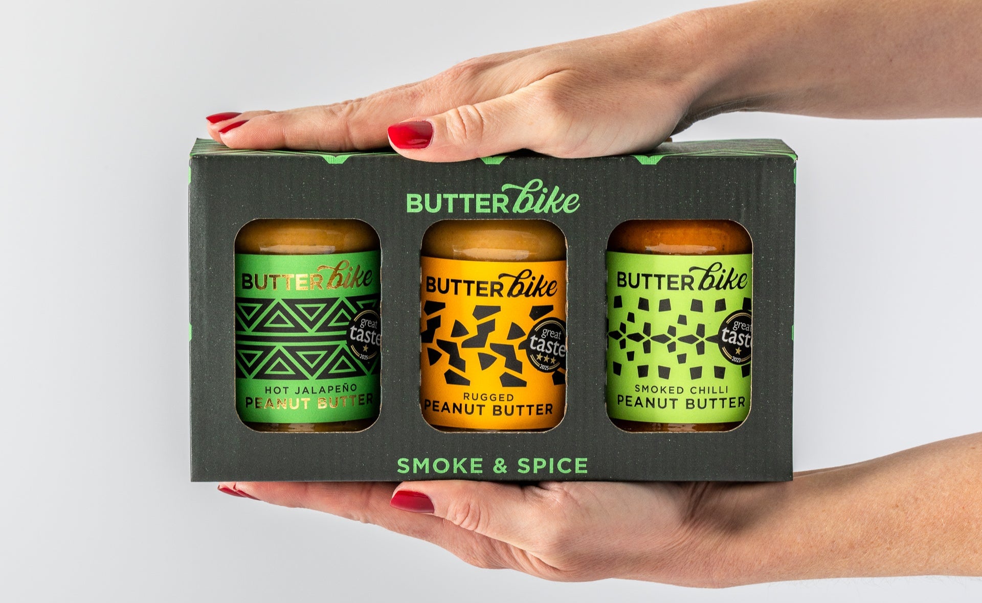 Butter Bike peanut butter jars in a box held by a hand on a light gray background